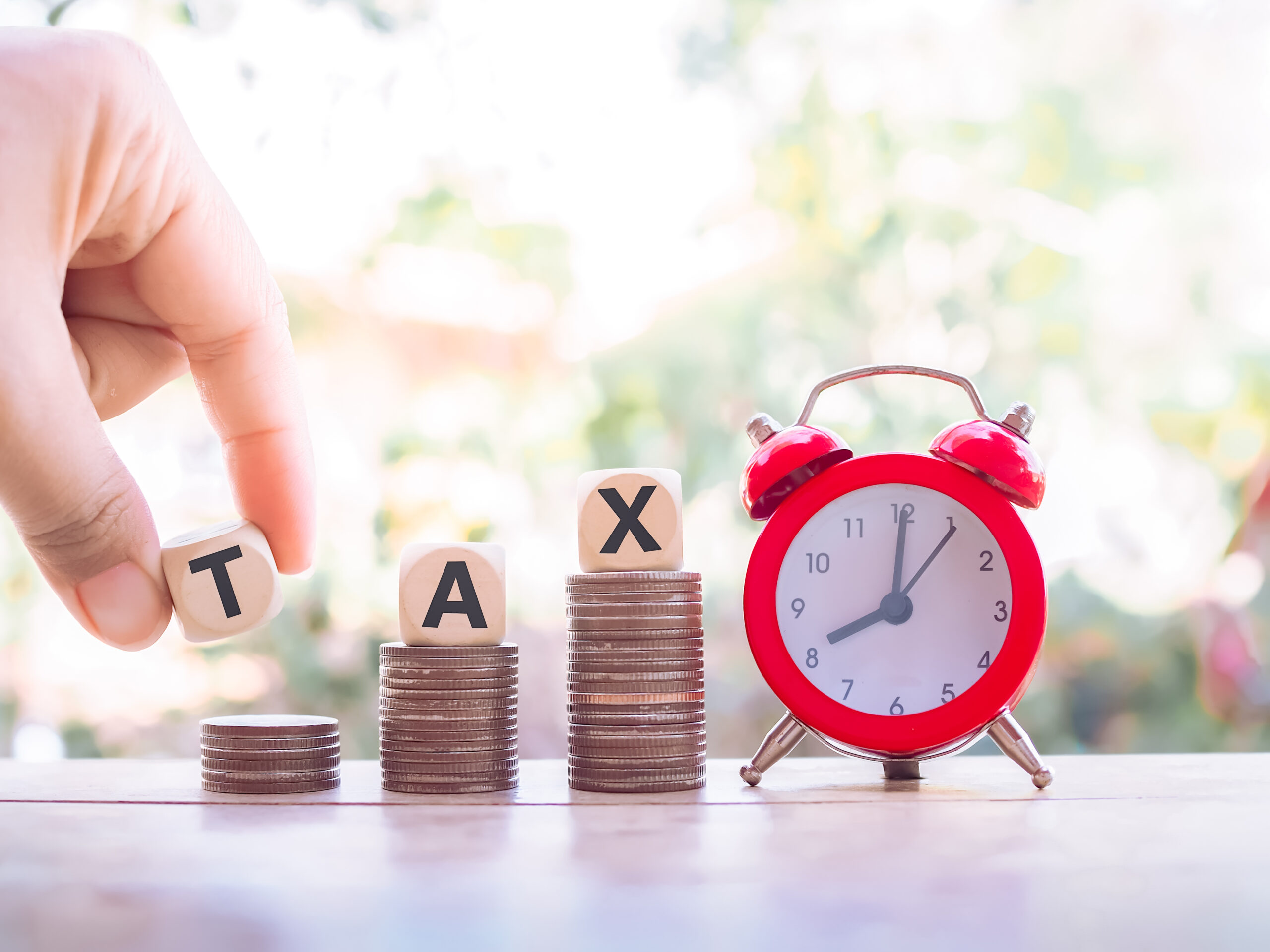 vecteezy_close-up-hand-holding-wooden-block-with-word-tax-on-stack-of_30534455