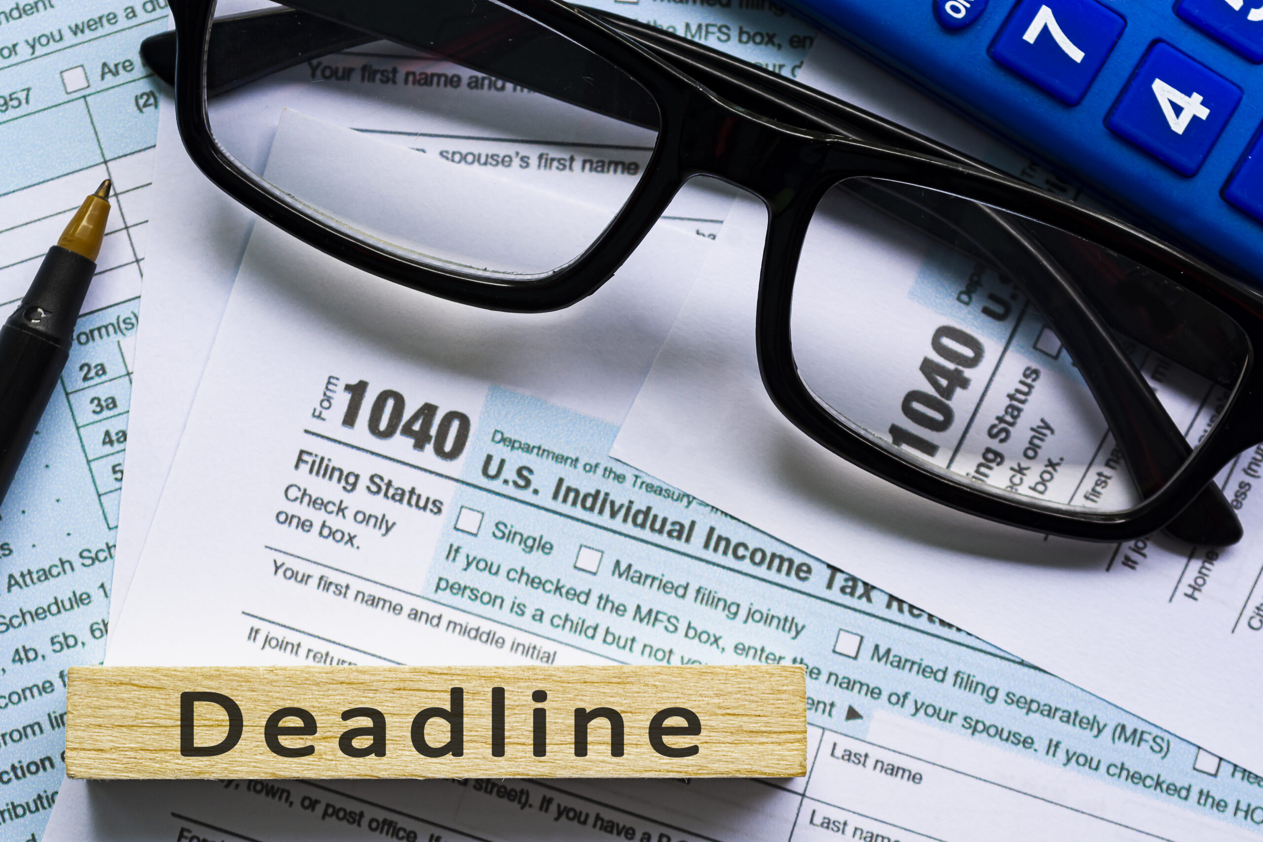 Deadline text on wooden block with Tax forms 1040. U.S Individual Income Tax.